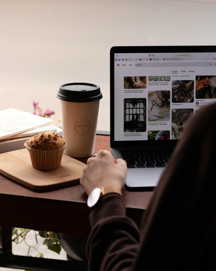 A cozy workspace setup with a coffee cup, muffin, and laptop creates a productive ambiance.