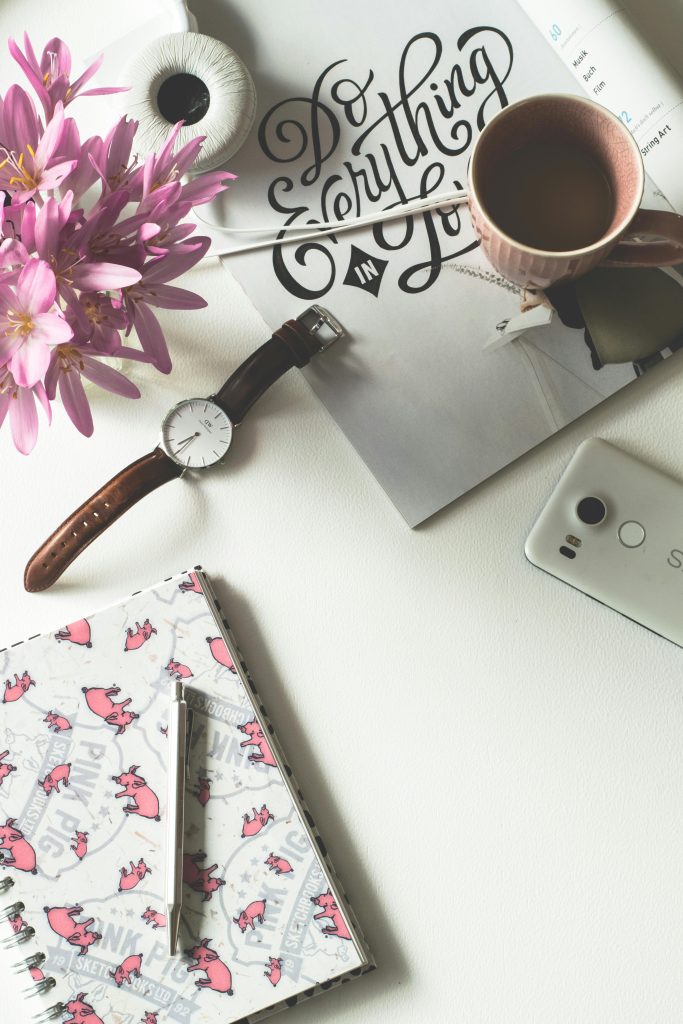 Brown Mug Near Watch and Flower on White Surface