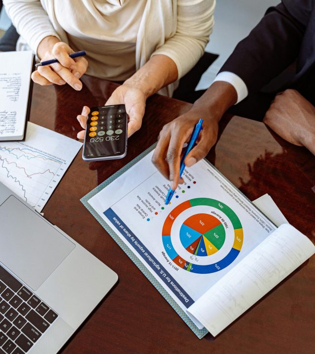 Two business professionals discussing financial documents and strategies at an office desk.