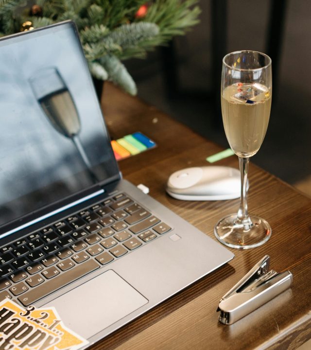 A cozy holiday-themed workspace featuring a laptop and a glass of champagne.