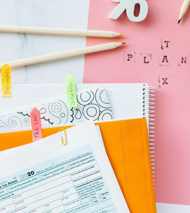 Overhead view of tax documents, percentage sign, and stationery items on pastel paper.