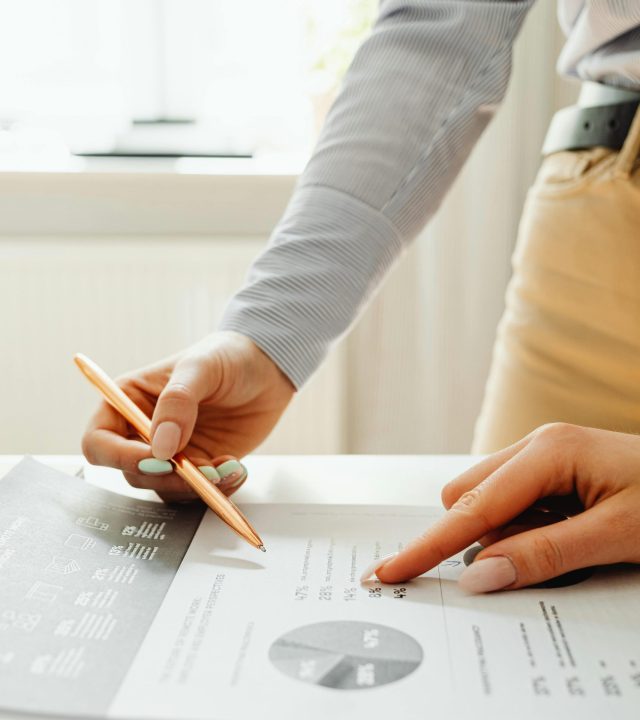 Close-up of hands reviewing financial documents and graphs in an office setting.