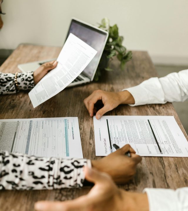 Two people reviewing documents at a wooden table during a business meeting.
